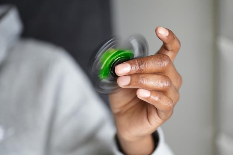 Hand holding and spinning a green fidget spinner.